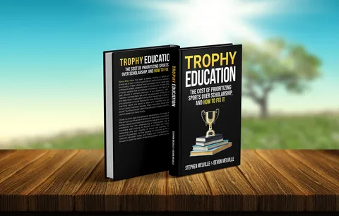 A black book titled Trophy Education displayed on a wooden table outdoors with a blurred green landscape and bright sky in the background.